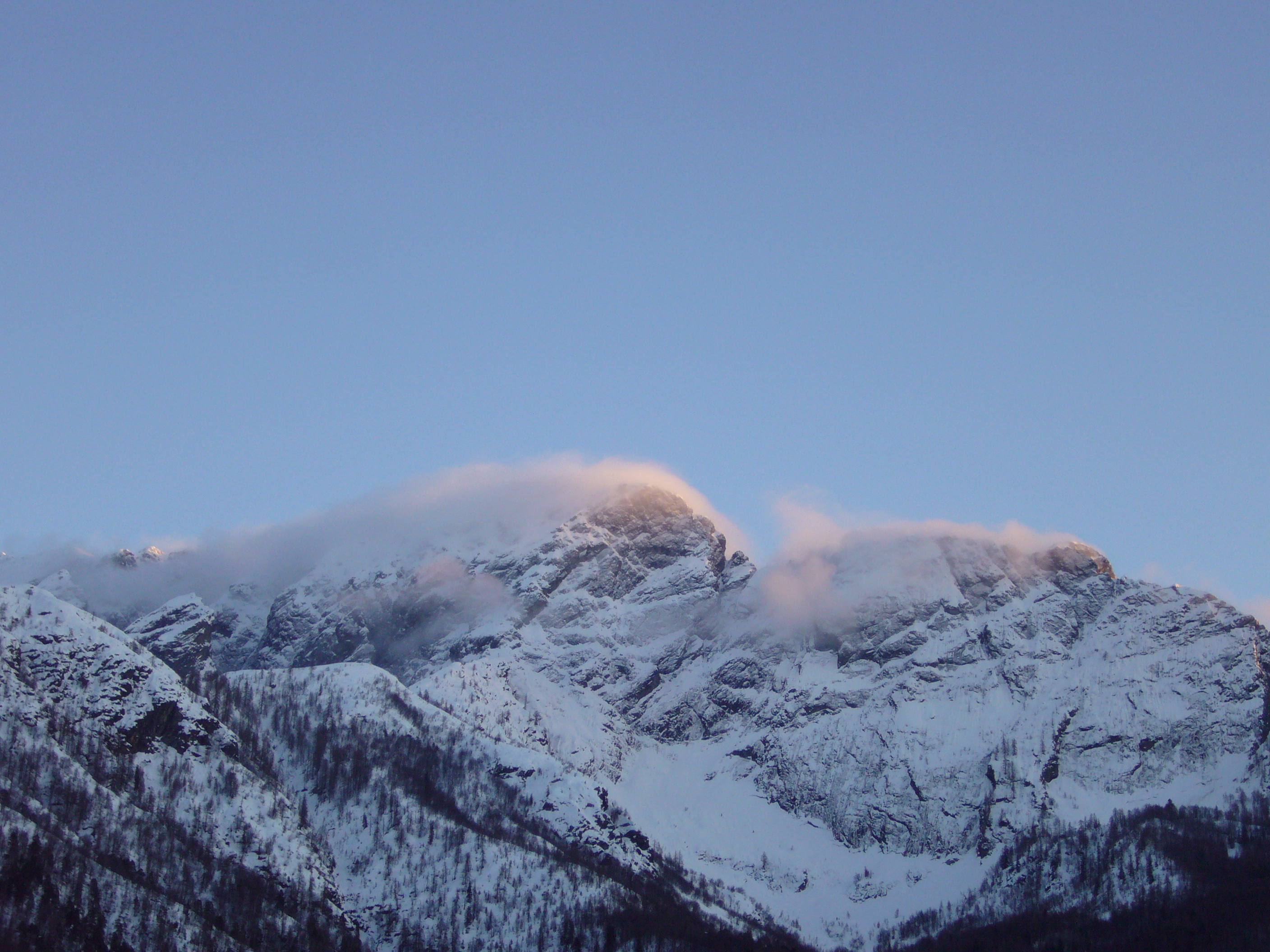 Cloud drifting over the snow-covered summit and wooded slopes of Mount Gridone.